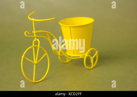 Giocattolo di souvenir bicicletta metallico con un secchio su uno sfondo verde scuro Foto Stock