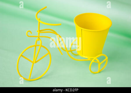 Giocattolo di souvenir bicicletta metallico con un secchio su uno sfondo verde Foto Stock