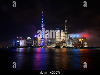 Vista della Torre di perla e skycrapers circostante di notte attraverso il fiume Huang Pu come visto da shanghai Bund, Shanghai, Cina. Foto Stock