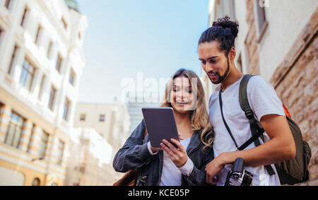 Turisti che utilizzano strumenti di navigazione per esplorare la città. L uomo e la donna di esplorare la città con accessori da viaggio. Foto Stock