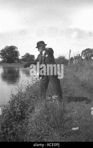 1930s, foto storiche che mostra un anziano gentiluomo a pesca di un argine indossando un pezzo di tre business suit e cappello bowler, Inghilterra, Regno Unito. Foto Stock