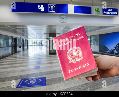 Persona in possesso di passaporto italiano in airport area controllo passaporti, composito digitale Foto Stock