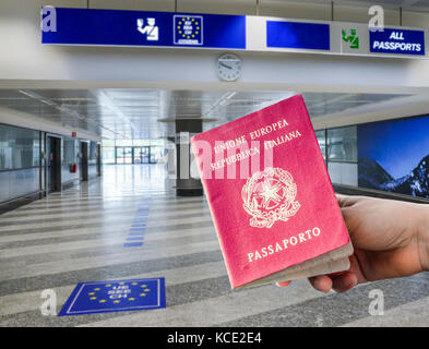 Persona in possesso di passaporto italiano nella zona di controllo dei passaporti aeroportuali, formato digitale Foto Stock