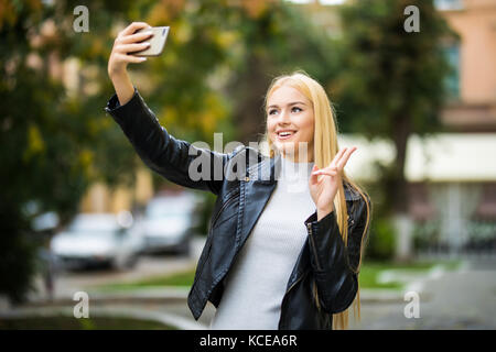 Ragazza giovane prendere selfie da mani con il telefono acceso estate città street. Foto Stock