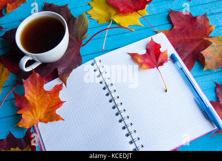 Tazza di caffè circondato da foglie di autunno sul tavolo. Foto Stock