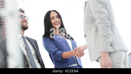 Business donna sorridente e facendo una stretta di mano in ufficio Foto Stock