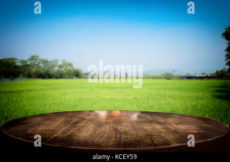 Messa a fuoco selezionata vuota brown tavolo in legno e cornfield prato o la sfocatura dello sfondo con bokeh immagine. per il fotomontaggio o display del prodotto. Foto Stock