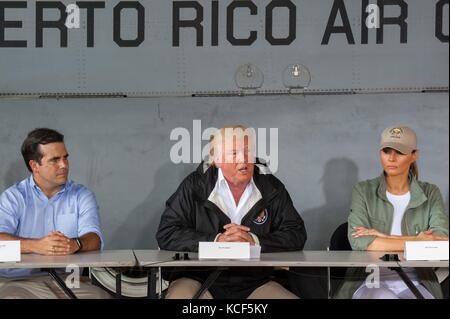 Carolina, Porto Rico. 03 ottobre 2017. Il presidente degli Stati Uniti Donald Trump, al centro, commenta come Porto Rico Gov. Ricardo Roselló, a sinistra, e la First Lady Melania Trump guardano durante una discussione sugli sforzi di soccorso dopo l’uragano Maria alla base della Guardia Nazionale aerea di Muñiz 3 ottobre 2017 a Carolina, Porto Rico. Credit: Planetpix/Alamy Live News Foto Stock