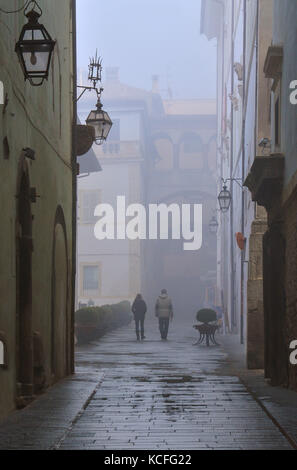 Spoleto (Italia) - un nebbioso giorno cadono nel suggestivo borgo medievale nella regione Umbria. La fitta nebbia crea un atmosfera suggestiva con raggi solari Foto Stock