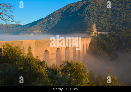 Spoleto (Italia) - un nebbioso giorno cadono nel suggestivo borgo medievale nella regione Umbria. La fitta nebbia crea un atmosfera suggestiva con raggi solari Foto Stock