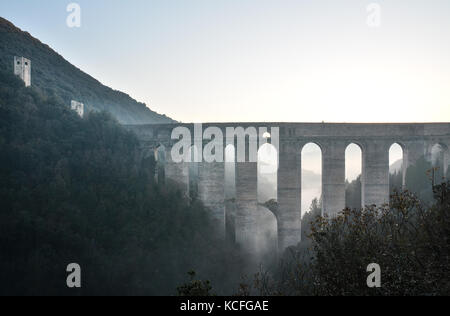 Spoleto (Italia) - un nebbioso giorno cadono nel suggestivo borgo medievale nella regione Umbria. La fitta nebbia crea un atmosfera suggestiva con raggi solari Foto Stock