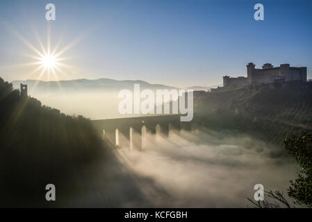 Spoleto (Italia) - un nebbioso giorno cadono nel suggestivo borgo medievale nella regione Umbria. La fitta nebbia crea un atmosfera suggestiva con raggi solari Foto Stock