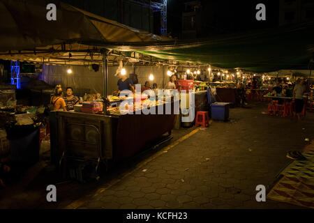 Un cibo asiatico fornitore, la vendita di cibo di strada a Phnom Penh il mercato notturno, in Cambogia. Il cibo è principalmente fritti e a buon mercato e di sperimentare la cucina asiatica. Foto Stock