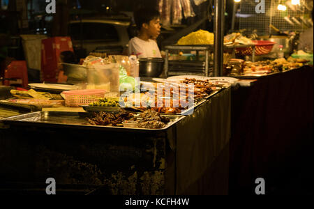 Un cibo asiatico fornitore, la vendita di cibo di strada a Phnom Penh il mercato notturno, in Cambogia. Il cibo è principalmente fritti e a buon mercato e di sperimentare la cucina asiatica. Foto Stock