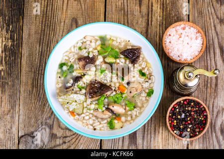 Zuppa vegetariana con funghi e farro per pranzo sul tavolo di legno Foto Stock