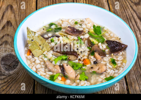 Zuppa vegetariana con funghi e farro per pranzo sul tavolo di legno Foto Stock