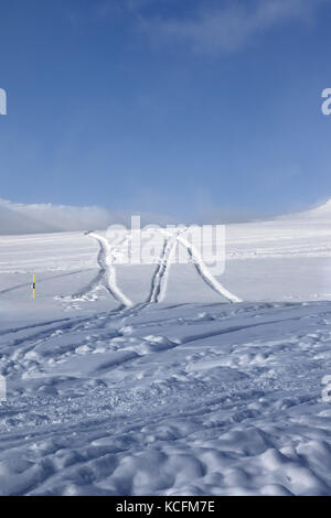 Fuori-pista di piste da sci con neve nuovo-caduta e tracce da sci, snowboard dopo la nevicata. montagne del Caucaso in sun sera d'inverno, georgia, regione gu Foto Stock