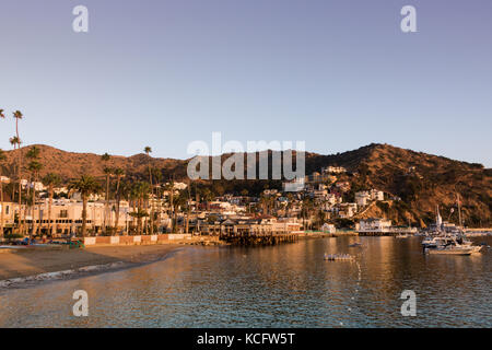 La mattina presto, sunrise n avalon porto guardando verso la spiaggia e la piccola città con barche ormeggiate nella baia, isola di attrazione turistica tranquilla un divertimento Foto Stock