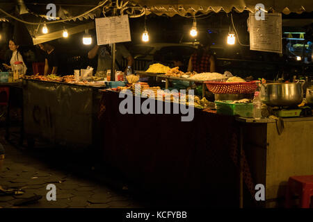 Un cibo asiatico fornitore, la vendita di cibo di strada a Phnom Penh il mercato notturno, in Cambogia. Il cibo è principalmente fritti e a buon mercato e di sperimentare la cucina asiatica. Foto Stock