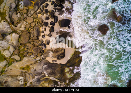 Vista aerea che guarda le onde del mare di colpire le rocce Foto Stock