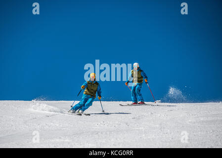 Due maschi gli sciatori si susseguono verso il basso una pista girando francesi nella località alpina di Courchevel. Foto Stock