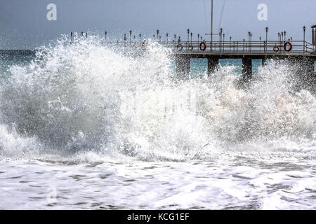 Grande mare tempestoso schizzi d'onda contro pier Foto Stock