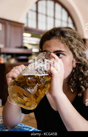 Giovane donna adulta è bere un grande vaso di birra nel ristorante con b Foto Stock