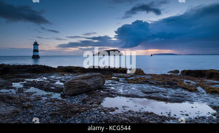 Immagine a colori di penmon faro in Anglesey, rocce e mare all'alba. Foto Stock