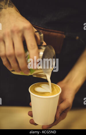 Barista versando il caffè alla tazza Foto Stock