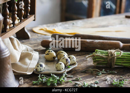 Ingredienti per fare la pasta fatta in casa, mattarello, uova di quaglia, asparagi sul tavolo di legno Foto Stock
