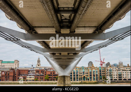 Edilizia e architettura in mostra attraverso la parte inferiore del Millennium Bridge, un passaggio pedonale che attraversa il fiume Tamigi a Londra, Inghilterra, Regno Unito. Foto Stock