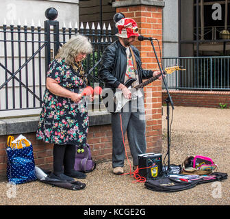 Suonatore ambulante eccentrico / buskers: vecchi donna e uomo, suonare la chitarra elettrica, con microfono, amplificatore e maracas. South Bank di Londra, Inghilterra, Regno Unito. Foto Stock