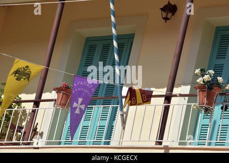 Alcuni vivacemente colorato bunting e decorazione appeso alla ringhiera di un balcone sull'isola greca di Corfu con verde chiuse le porte dietro. Foto Stock