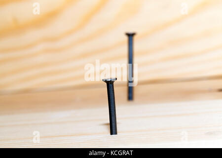 Martellato nel listone di legno di pino piano parecchi chiodi metallici durante i lavori di costruzione. focus sul primo chiodo. foto close up Foto Stock