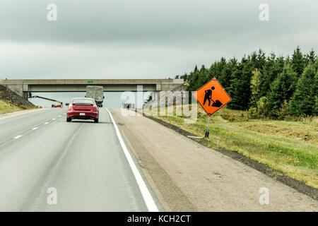 Orange lavoratore edile segno a una strada in lontananza sulla Trans Canada Foto Stock