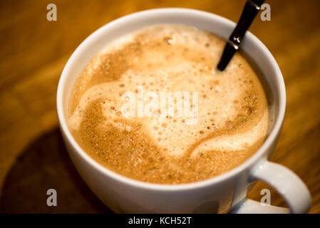 Accessori per caffè cappuccino con schiuma di latte e bolle in un bianco  tazza di porcellana sul piattino in legno marrone a tavola Foto stock -  Alamy