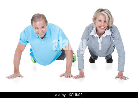 Felice Coppia matura facendo push-up isolati su sfondo bianco Foto Stock