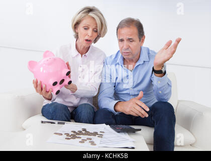 Ritratto di scioccato giovane azienda piggybank a casa Foto Stock