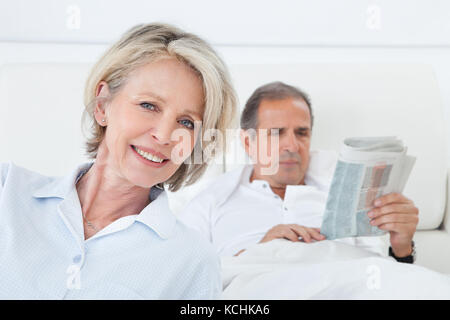 Felice Coppia donna seduta davanti all uomo che legge il giornale Foto Stock