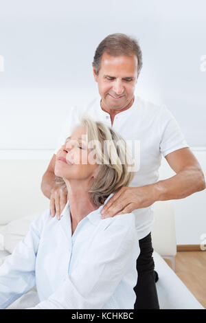 Uomo maturo massaggiante spalla donna in letto Foto Stock