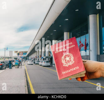 Persona in possesso di un passaporto italiano con fuori fuoco aeroporto entrata in background Foto Stock