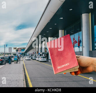 Persona in possesso di passaporto generico con fuori fuoco aeroporto entrata in background Foto Stock