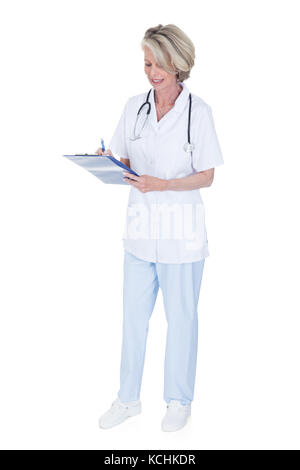 Femmina matura medico iscritto negli appunti su sfondo bianco Foto Stock