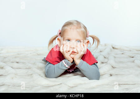 Bambina con le mani sul mento è sdraiato Foto Stock