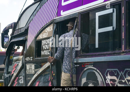 Conduttore di autobus sorge nella porta in ora di punta, Nairobi, Kenia Foto Stock