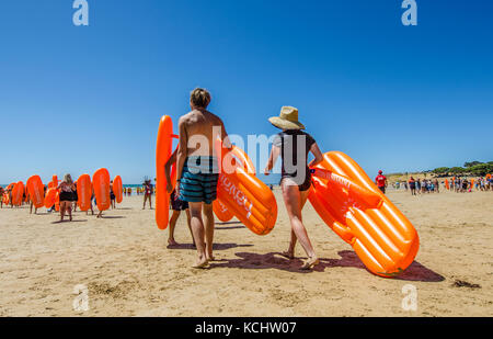 Beachgoers portante Havianas gonfiabile flip-flop in surf in Australia annuale evento della durata di un giorno, accogliente angolo, Torquay, surf Coast, Victoria, Australia Foto Stock