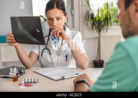 Medico spiegando la gamba caviglia raggi X al paziente Foto Stock