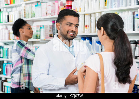 Giovane farmacista assistendo il cliente femmina Foto Stock