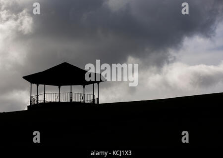 Silhouette di un palco per spettacoli in cima alla collina contro il buio, moody nuvole nel cielo Foto Stock