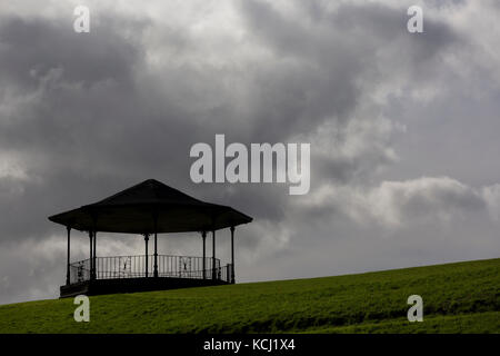 Bandstand alla sommità della collina contro il buio, moody nuvole nel cielo, verde erba in primo piano Foto Stock